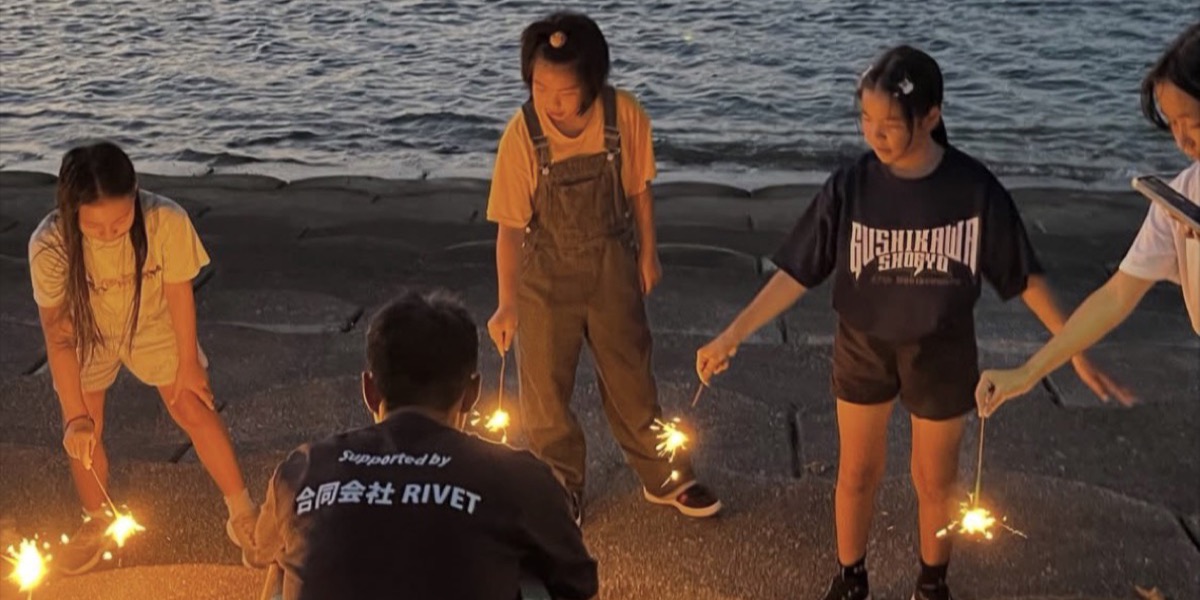 夕暮れの海辺で花火をする子どもたち（お泊まり遠足・2026年7月23〜24日・うるま市宮里）