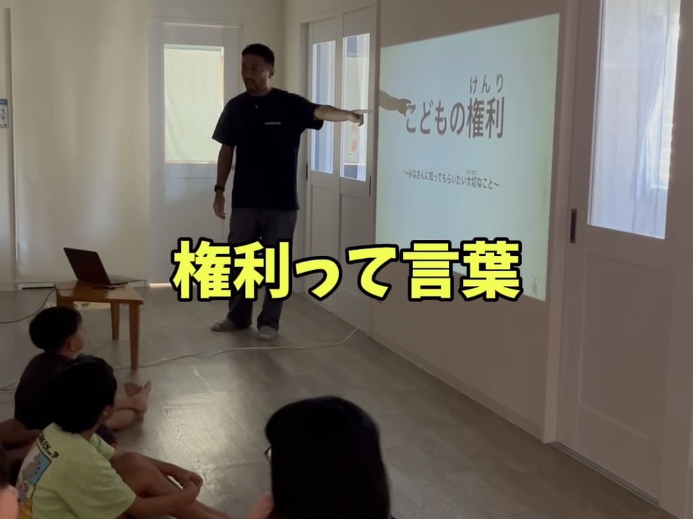 「こどもの権利」のスライドを前に、子どもたちへ話をする代表理事・須藤竜