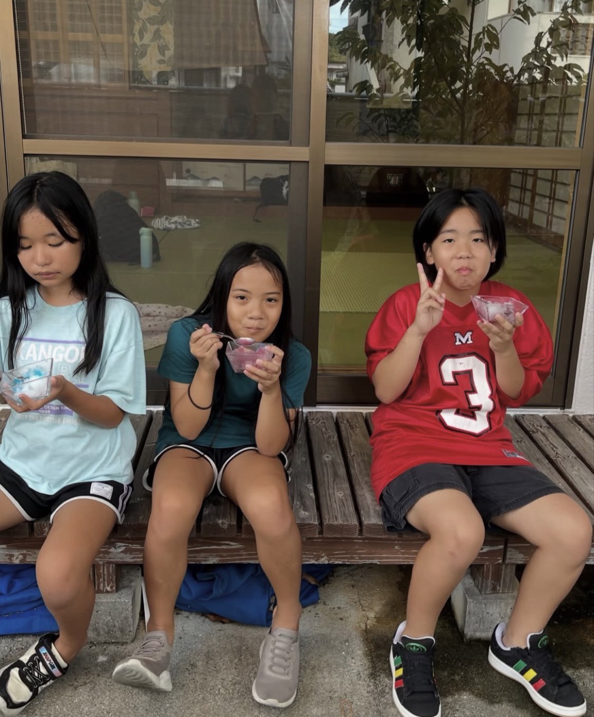 縁側に並んでかき氷を食べる子どもたち