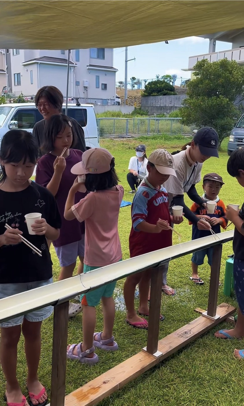 樋の両側に並んでそうめんをすくう子どもたち
