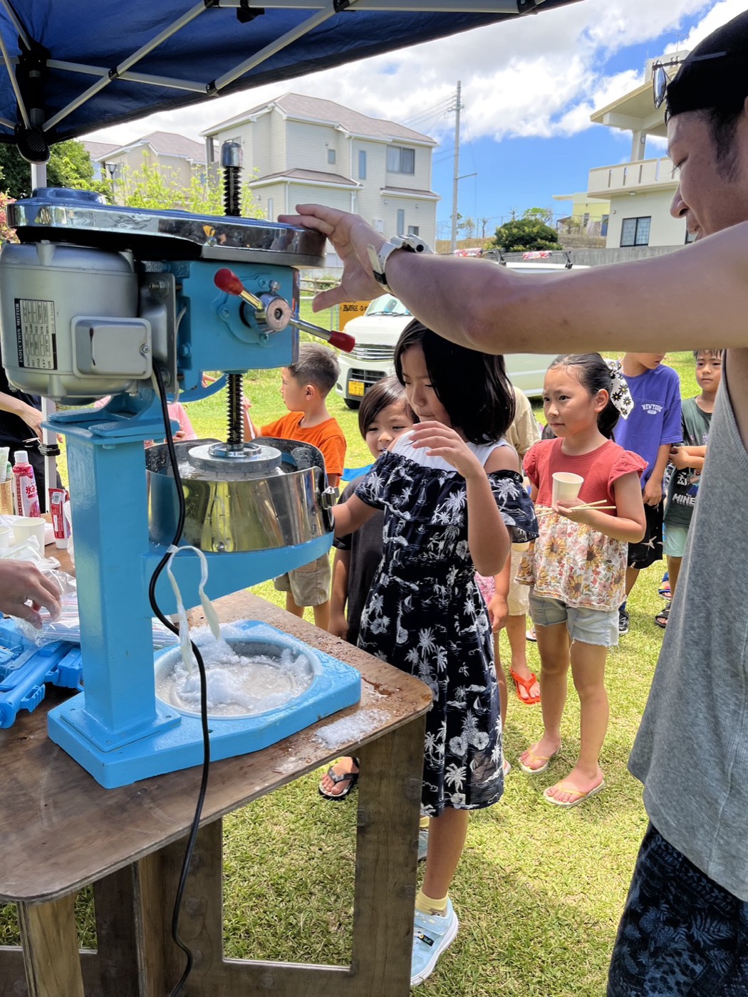 かき氷機の前に並び、できあがったかき氷を受け取る子どもたち