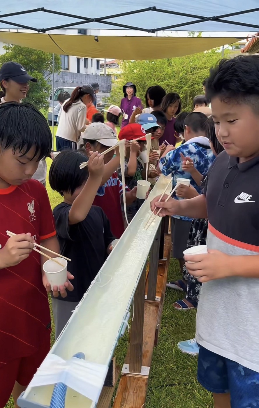 樋を流れてくるそうめんを箸ですくい上げる子どもたち